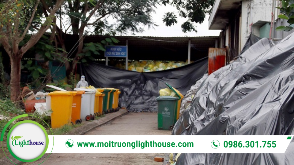 Khu lưu giữ tạm thời chất thải nguy hại ngoài trời với các thùng phân loại và bao chứa được che phủ.